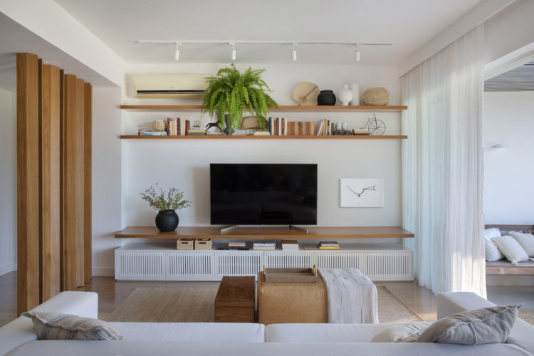 Sala de Tv em um apartamento de 200m2 em São Conrado. Prateleiras em madeira e rack em madeira branca com portas ripadas