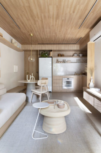 Apartamento aconchegante, decorado em tons claros, cozinha incorporada a sala, teto revestido em madeira clara 