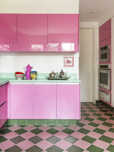 Cozinha com armários na cor rosa, e piso xadrez nas cores verde e rosa