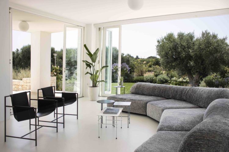 Sala com janelões abertos que integram com a natureza, espaço interno e externo integrados 