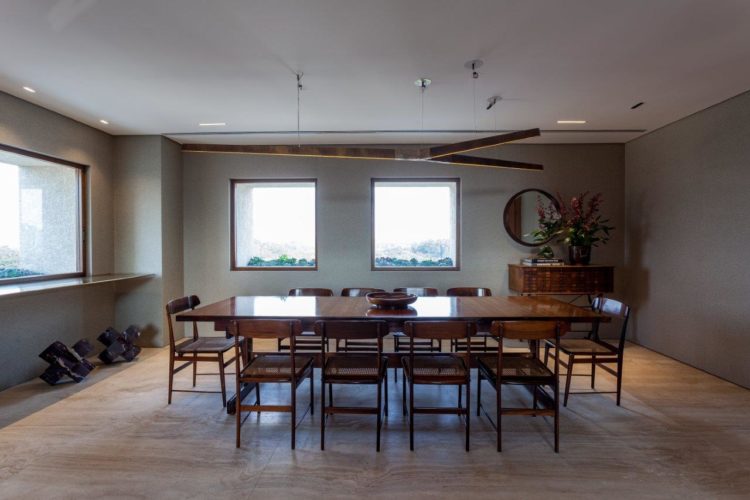 Sala de jantar, com mesa e cadeiras em madeira, janelas quadradas dão a ilusão de serem quadros