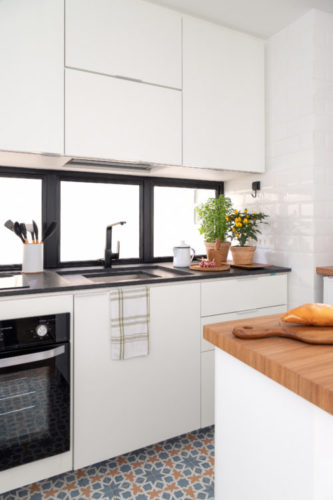 Cozinha compacta com armários brancos e bancada preta