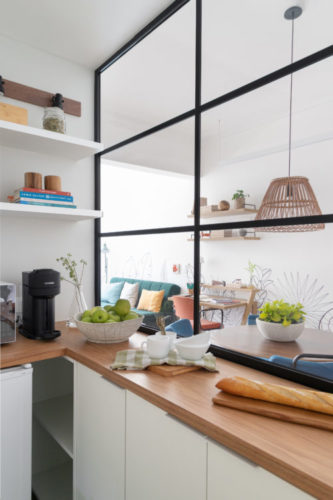 Cozinha compacta, bancada seca em madeira e esquadria preta separando ambientes 
