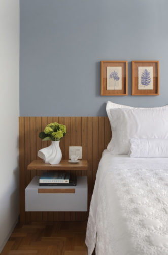Quarto com meia parede em azul claro acinzentado, e cabeceira em ripas de madeira