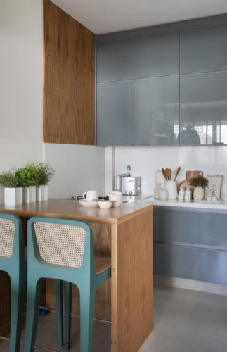 Cozinha integrada a sala, com bancada em madeira e armários na cor azul acinzentado