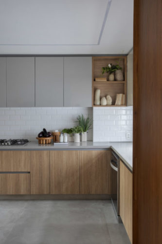 Cozinha com armários superiores cinza, da parte de baixo em madeira, e revestimento metro branco 