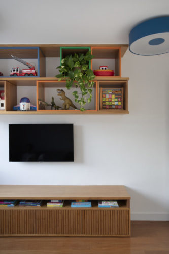 Nichos em madeira com a frente colorida, na parede em cima da tv