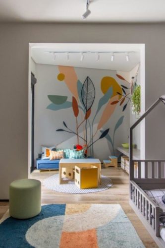 O quarto do segundo filho em estilo montessoriano e com muito espaço para brincar, na parede a fundo, pintura de folhagens feito á mão.