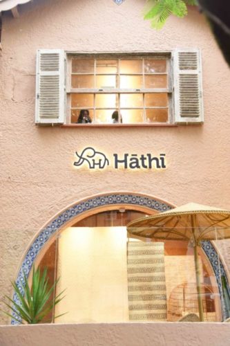Fachada da loja de tapetes Hatchi, em Ipanema. Fachada pintada em tom terroso, vitrine com arco revestido de azulejo.