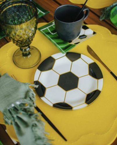 Mesa posta com tema de futebol, jogo americano amarelo, prato com estampa de bola