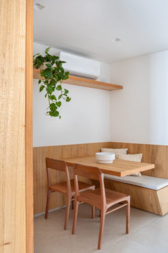 Canto alemão na cozinha; banco fixo de um lado, mesa em madeira e duas cadeiras.