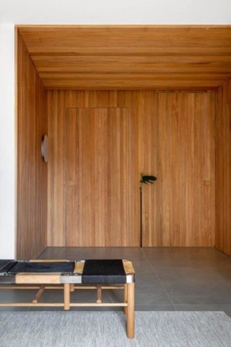 Hall de entrada, de um apartamento, todo revestido em madeira, camuflando as portas.