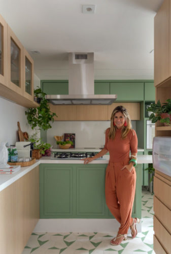 Foto da arquiteta Amanda Miranda na cozinha que ela projetou. Armários na cor verde menta.