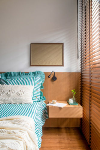 Cabeceira da cama em madeira e mesa lateral acoplada. Jogo de cama listrado em turquesa e branco
