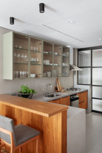 Cozinha com armários inferiores em madeira, armários superiores em vidro canelado