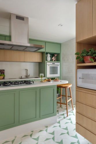 Cozinha com décor bem leve, armários na cor verde menta, com ilha com o tampo branco, piso em ladrilho hidráulico branco e verde. 