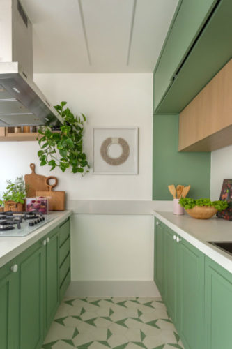Cozinha com tampos brancos e armários na cor verde menta.