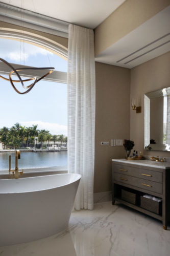 Banheiro em uma casa de 400m2 em Miami, que recebeu reforma completa. No banheiro, a banheira fica em frente a janela, que tem vista para o canal.
