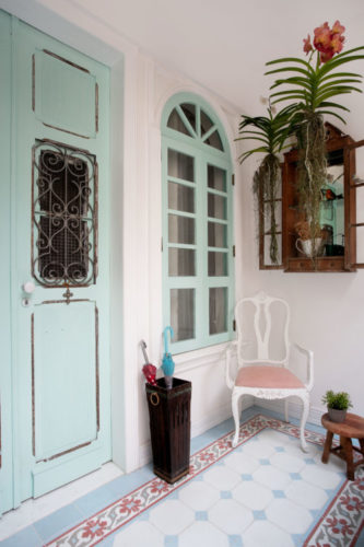 Varanda em uma charmosa casa de vila em Niterói. No piso, ladrilho hidráulico com as mesmas cores da fachada, rosa e azul claro, paletas candy colours 