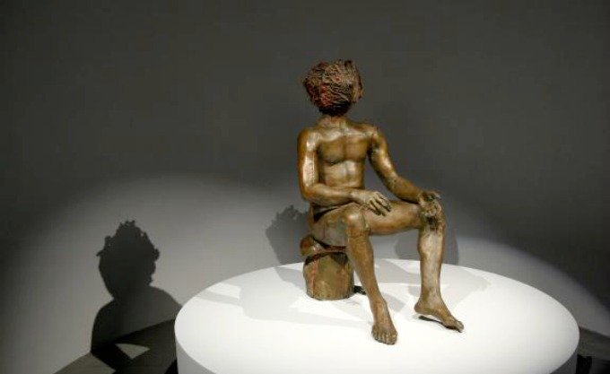 Escultura em bronze de homem com cabeças de repolho