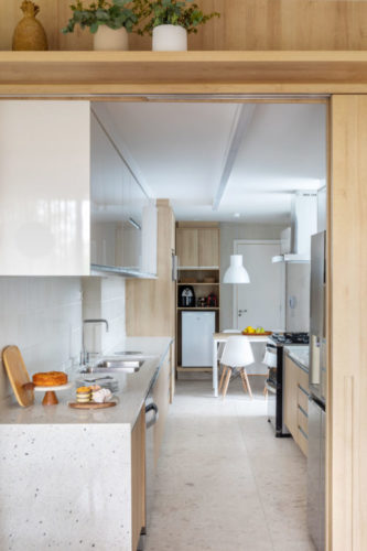 Cozinha com planta em corredor, com armários na em madeira clara.