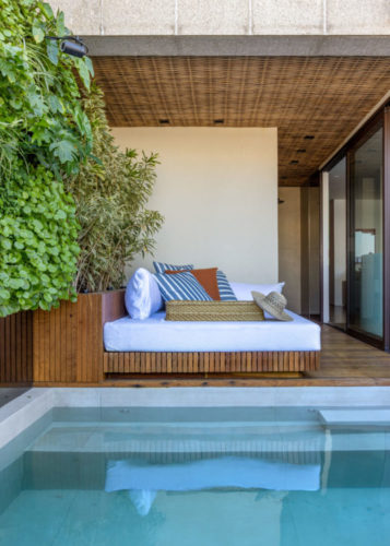 Cobertura com uma pequena piscina, e ao lado, uma parte fechada com o teto revestido em bambu e um grande futon branco