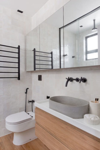 Banheiro na suíte do casal, revestimentos brancos, louça cinza e metais em preto.