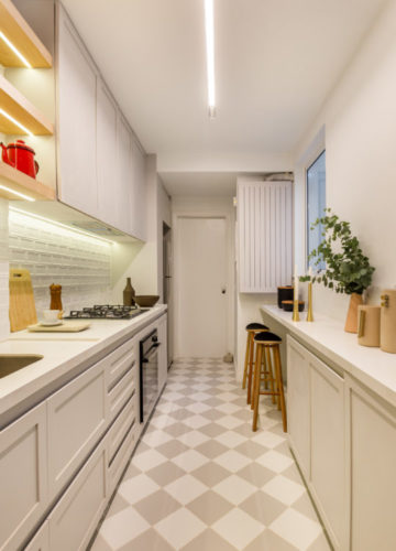 Cozinha clara, com armários brancos e piso xadrez em branco e bege.