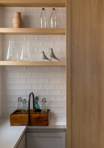 Detalhe de uma cozinha reformada. Fundo das prateleiras em azulejo tipo metro, armários em madeira