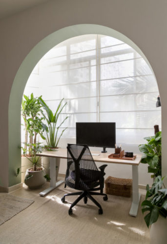 Varanda incorporada ao quarto, com um arco delimitando. Mesa de home office 