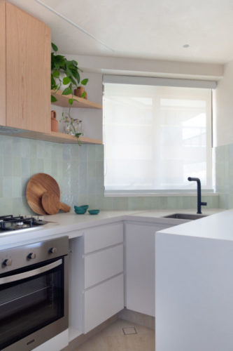 Cozinha com bancada a armários inferiores na cor branca, e armários superiores em madeira.