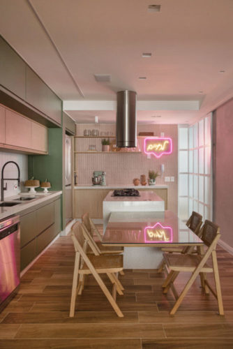 Verde, rosa e madeiras claras dão o tom deste apartamento de 160m2, em Ipanema, que a UP3 Arquitetura projetou para um jovem casal. São essas cores e a madeira que revestem as paredes e armários da cozinha, que ainda tem um neon na cor rosa.