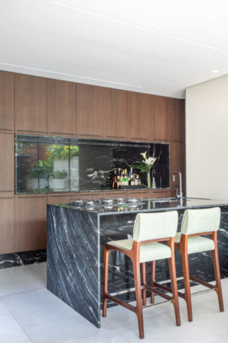 Área gourmet com bancada alta em mármore preto e banquetas de design