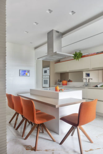 Cozinha com ilha e mesa acoplada, cadeiras em tecido laranja
