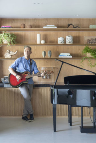 O morador Carlos Dantas, ao lado do piano e com um violão na mão