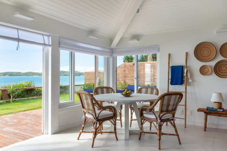 Mesa redonda e cadeiras de palha, na mesa em uma casa em Búzios de frente para o mar.