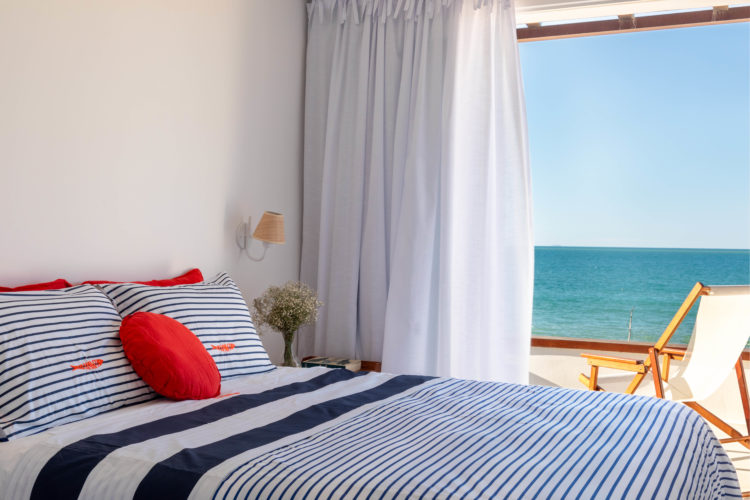 Quarto em uma casa em Búzios de frente para o mar, com enxoval de cama listrado em azul, branco e vermelho