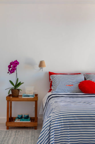 Quarto em uma casa em Búzios com a roupa de cama listrada de branco, azul e vermelho.