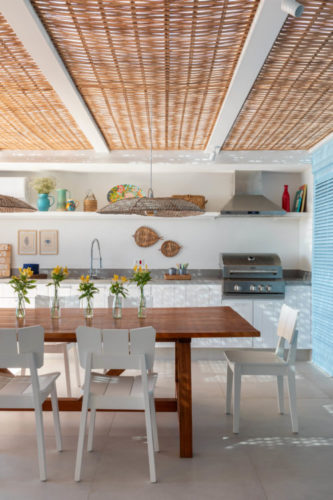 Casa em Búzios com venezianas azuis e área gourmet com vista para o mar. Teto forrado com esteiras de palha.