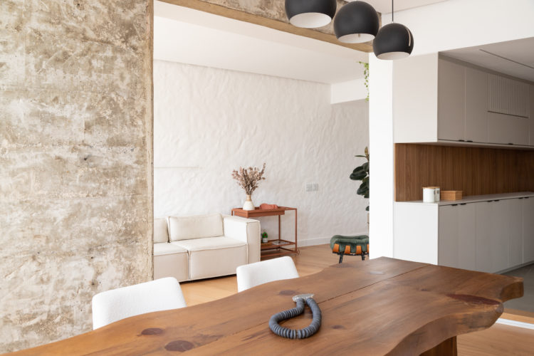 Vigas de concreto, reboco aparente e parede com textura artesanal dão o tom nesse apartamento de 130m2 em Ipanema.