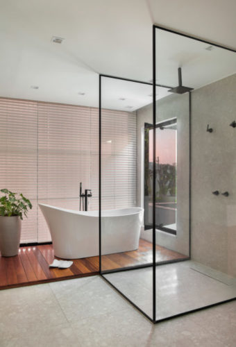 Banheiro com banheira e área do chuveiro com esquadria preta