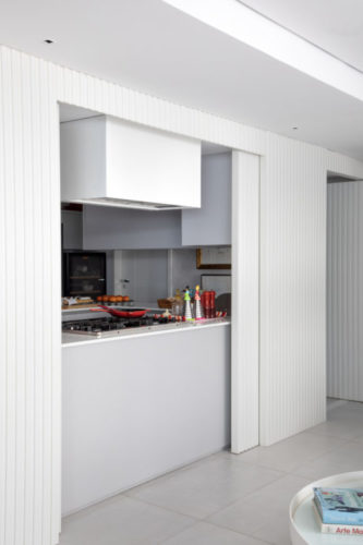 Em Recife, o novo lar de uma arquiteta e seu marido que tem a cozinha aberta para a sala quando grandes paineis em madeira ficam abertos.