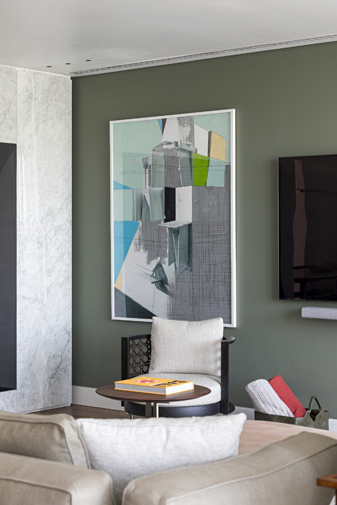 Um quadro com pintura abstrata, ao lado na tv, compõe a parede pintada de verde bem clarinho