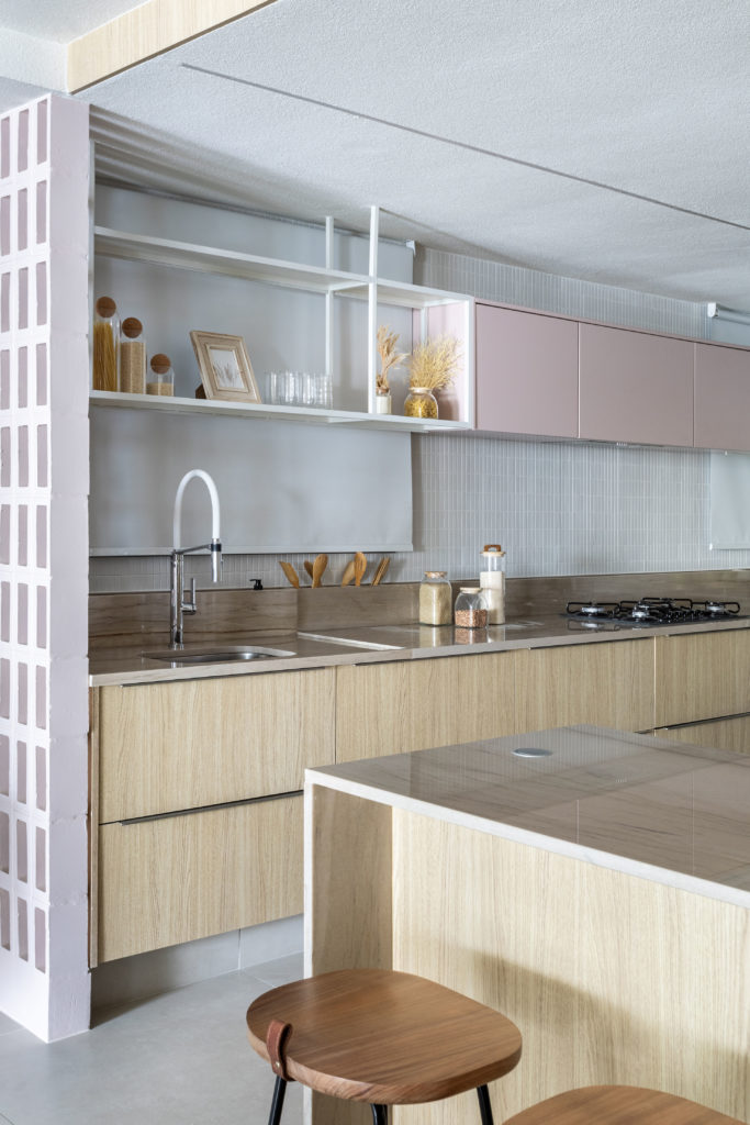 Cozinha com armários inferiores na em madaeira clara, e os superiores na cor rosa