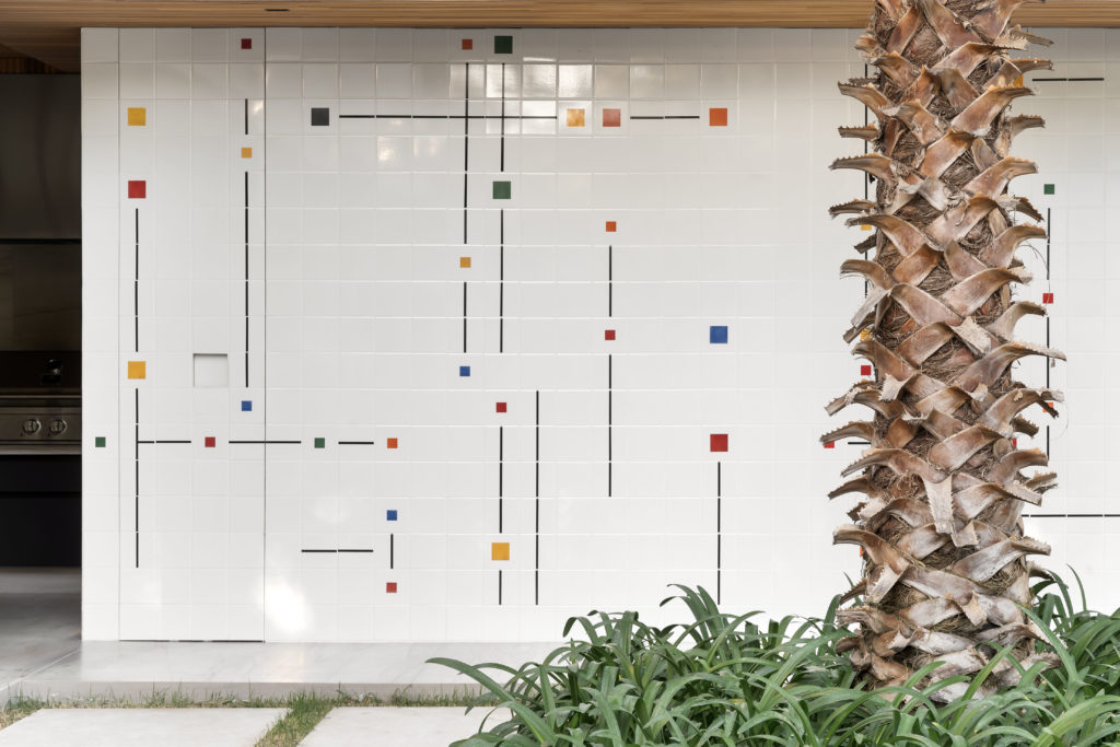 Painel em azulejos com desnhos, criado por um artista plastico, fica no jardim e camufla a entrada para a sauna