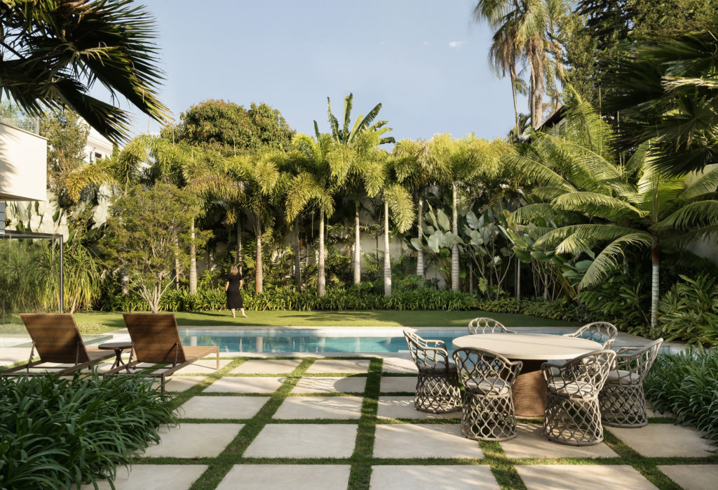 Na área da piscina, ao fundo, um paisagismo repleto de palmeiras.