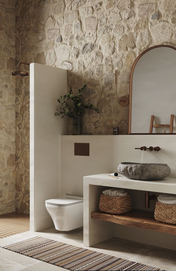Banheiro com paredes de pedra e cuba em pedra sabão