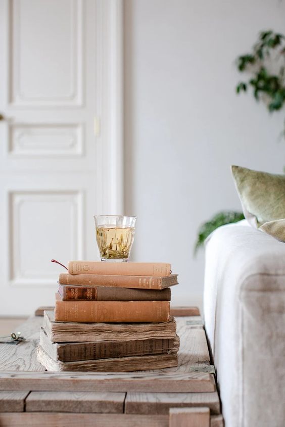 Um banquinho de madeira, com alguns livros em cima, e uma caneca de chá.
