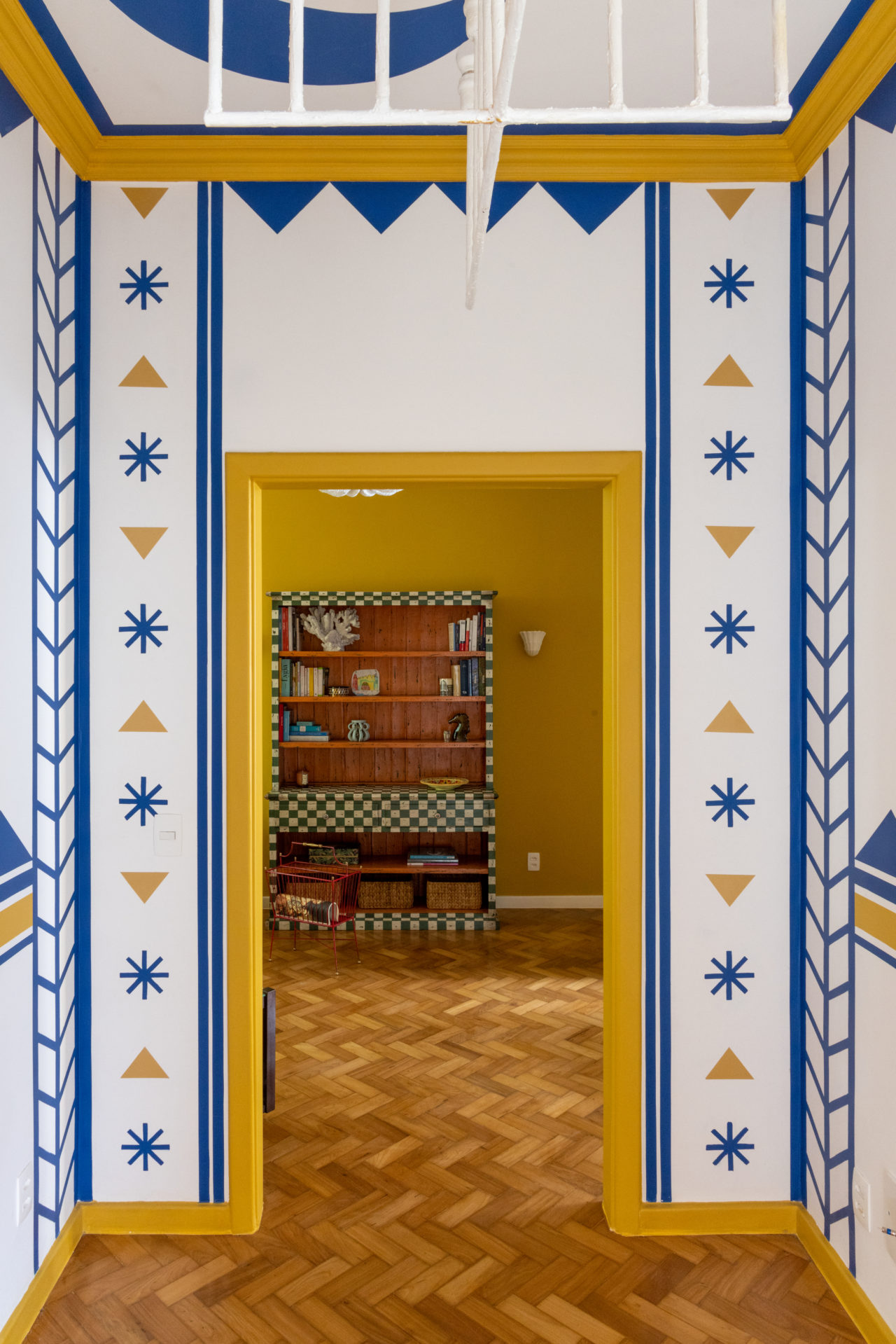 Hall dos quartos com pintura especialm nas cores branco, azul e amarelo.hall dos quartos (não existe corredor) tem inspiração em Calder, Miró e a cultura indígena, uma mistura quase alucinógena, toda desenhada por Jean e que traz mais alegria ainda ao apartamento.