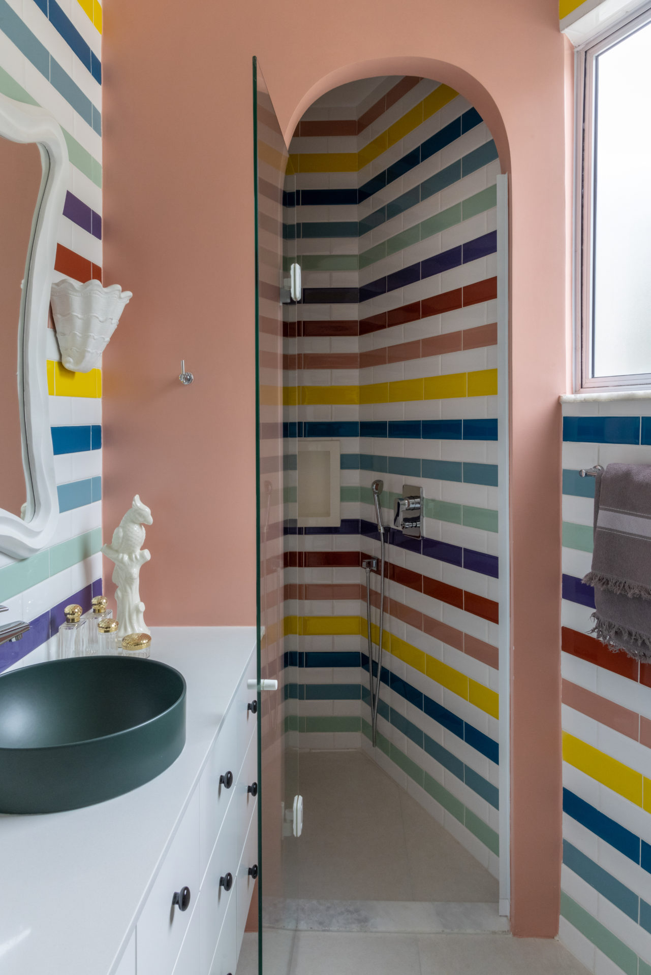 Banheiro com revesido com cerâmicas coloridas e formando faixas intercaladas com branco